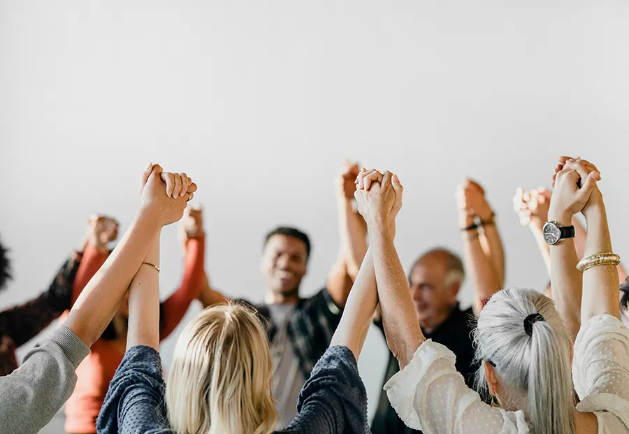 Group of people in a circle, holding hands with their hands in the air