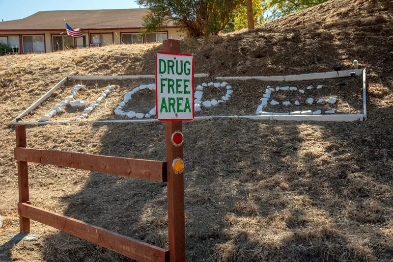 A sign reading, "Drug Free Area" with the word "Hope" formed by rocks on a hill in front of Bibett's